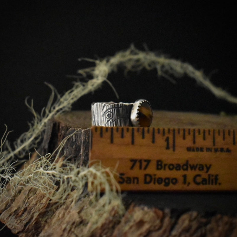 The side of the Tiger’s Eye Wide Bark Band Ring with a ruler for scale, measuring around 3/4 inches wide overall.