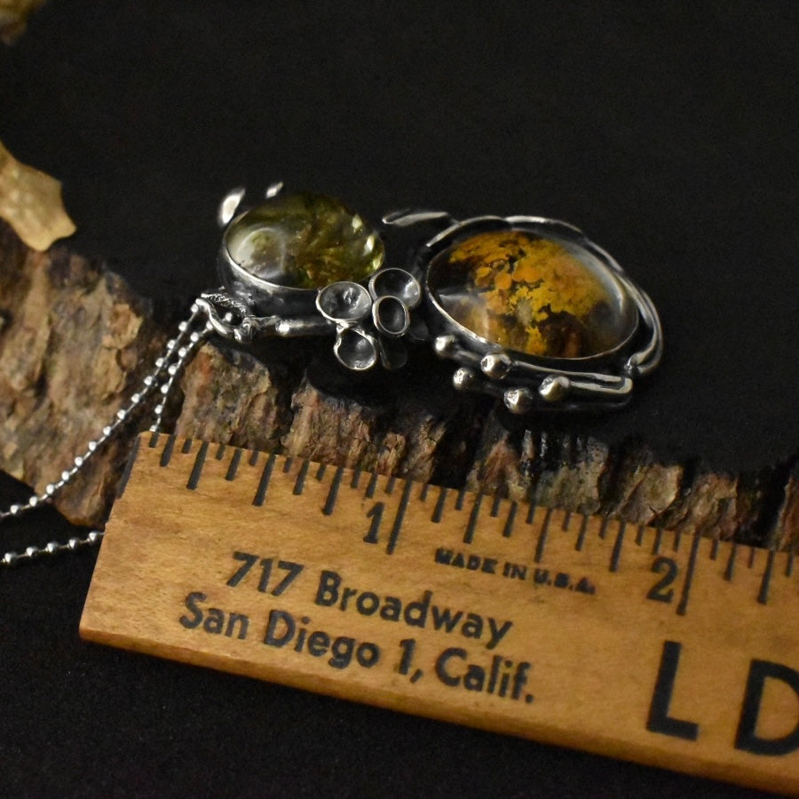 The Lichen Love Pendant with a ruler for scale, measuring around 1 7/8 inches long.