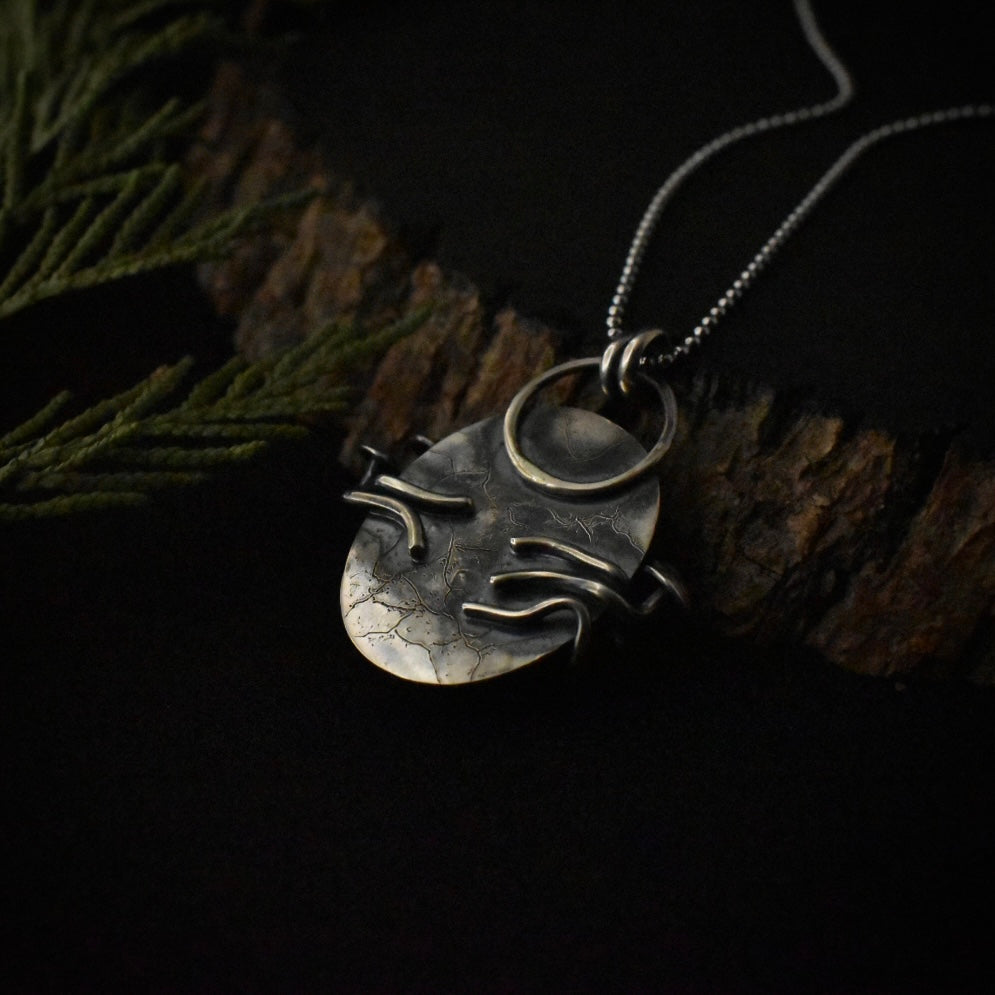 The back of the Black Onyx Classic Fungal Pendant, showing the details engraved underneath the setting and its sterling silver double bail.