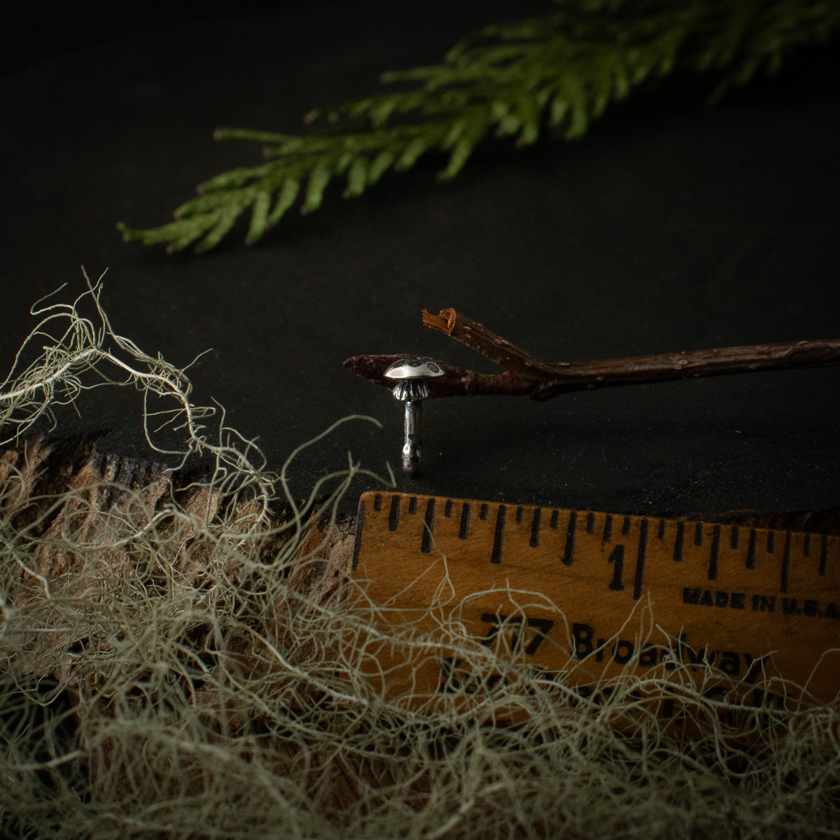The Amanita Lapel Pin with a ruler for scale, measuring around 1/4 inches wide.