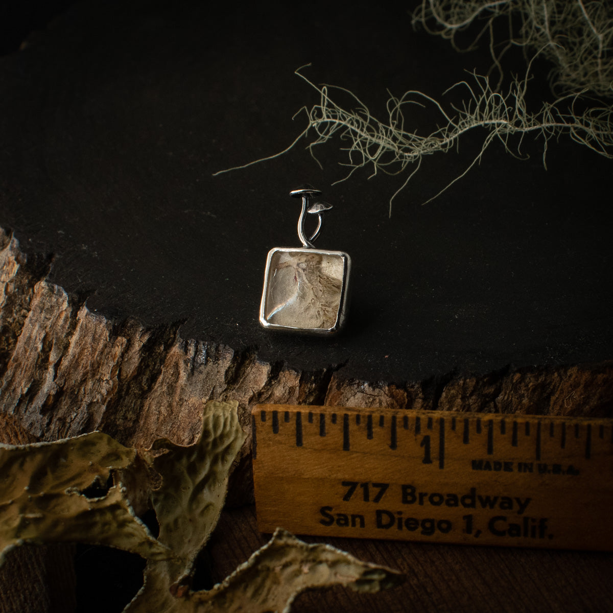 The Real Lichen Mycena Duo Lapel Pin with a ruler for scale, measuring around 1/2 inch wide.