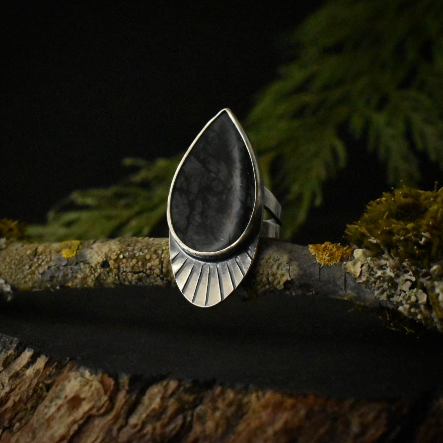 A handmade sterling silver statement ring, with a setting of deep dark gray picasso jasper, and stamped radiating lines.