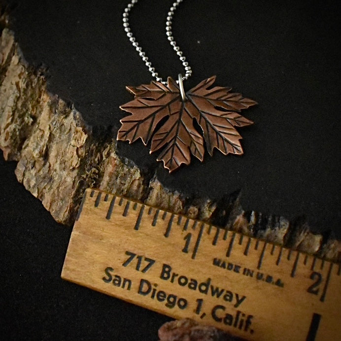 The Big Leaf Maple Pendant with a ruler for scale, measuring around 1 1/4 inches wide.