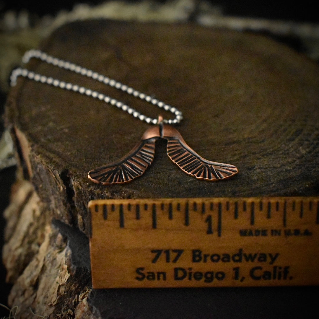 The Copper Helicopter Pendant with a ruler for scale, measuring around 1 1/4 inches wide.