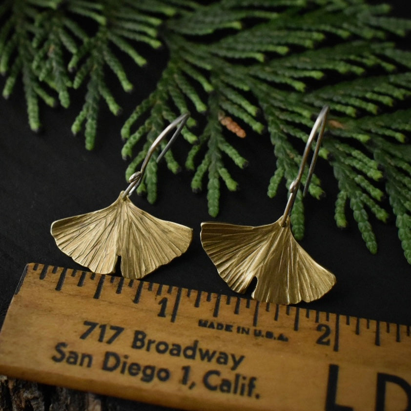 The Brass Gingko Leaf Earrings with a ruler for scale, each measuring around 1 inch wide.