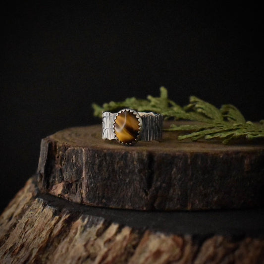 A handmade sterling silver statement ring, with lustrous tiger’s eye in a serrated bezel setting.