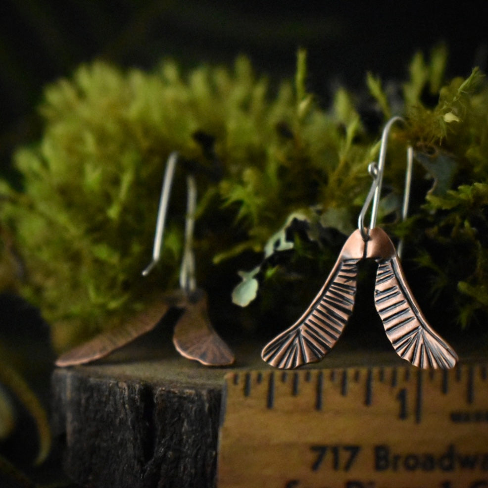 The Copper Helicopter Earrings with a ruler for scale, each measuring around 1 inch wide.
