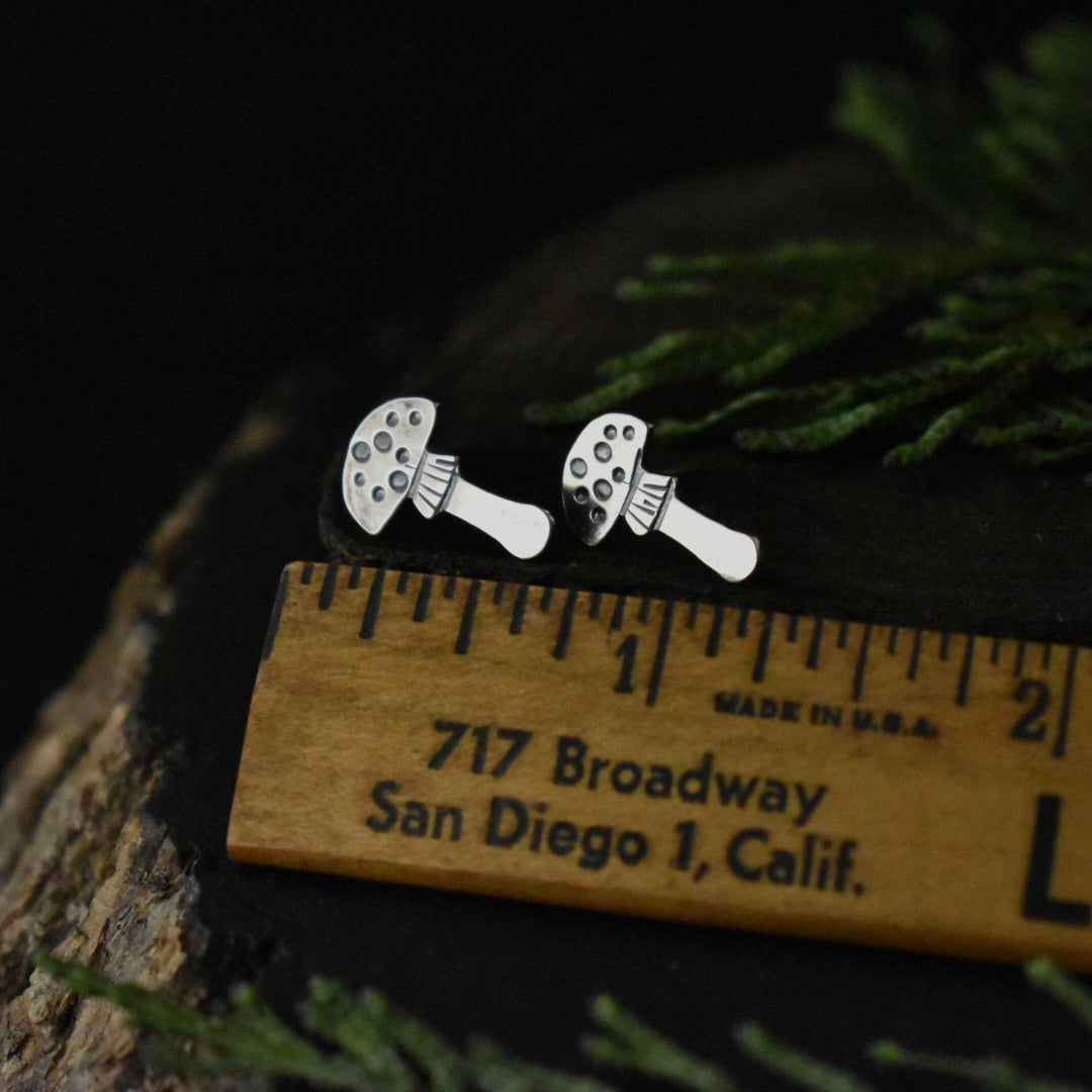 The Amanita Stud Earrings with a ruler for scale, each measuring around 5/8 inches long.