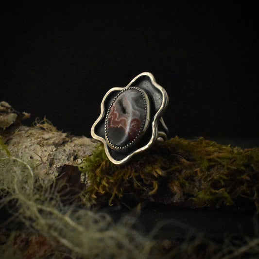 A handmade sterling silver statement ring, with a large setting of swirling red and gray crazy lace agate.