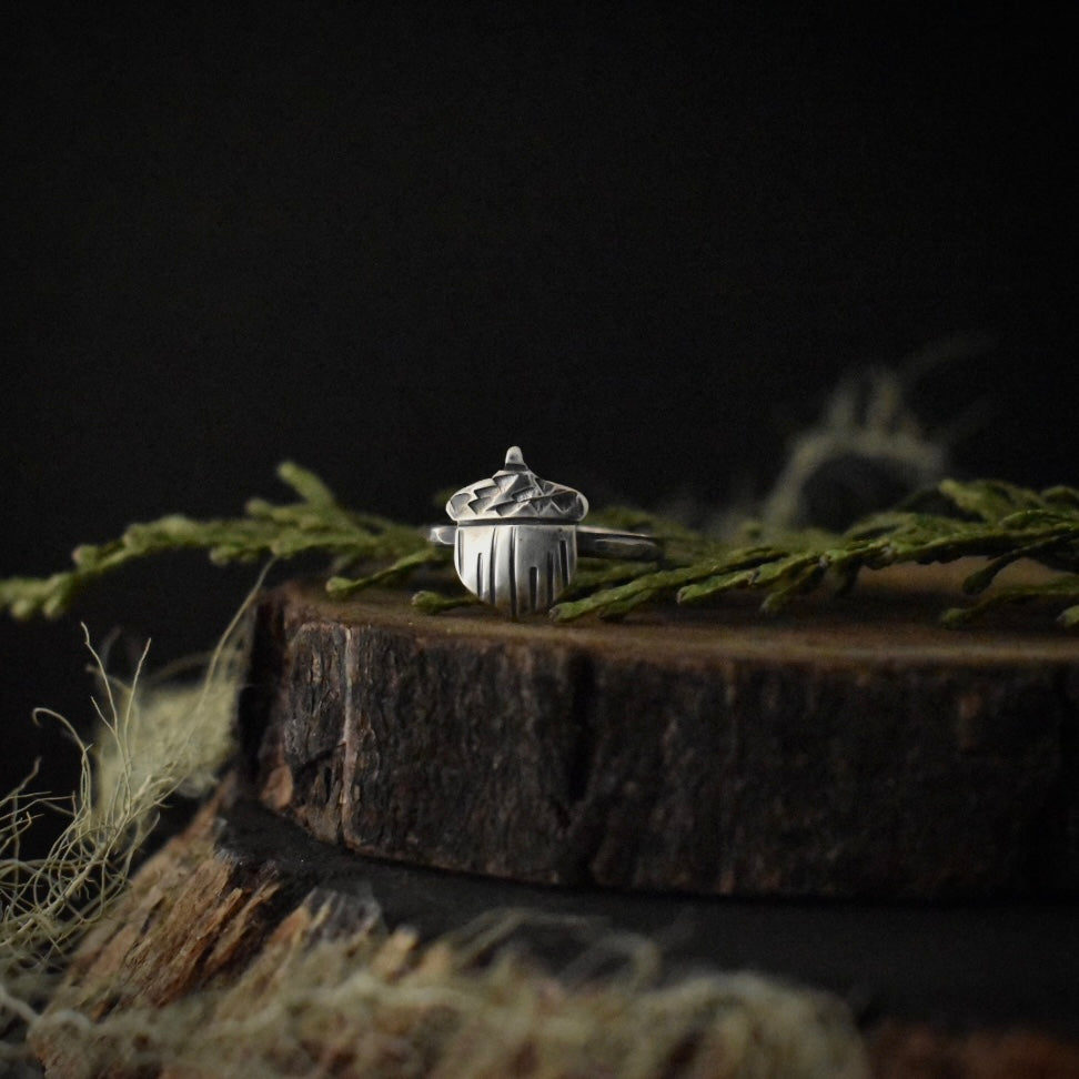 A handmade sterling silver ring, stamped and textured to look like an acorn.