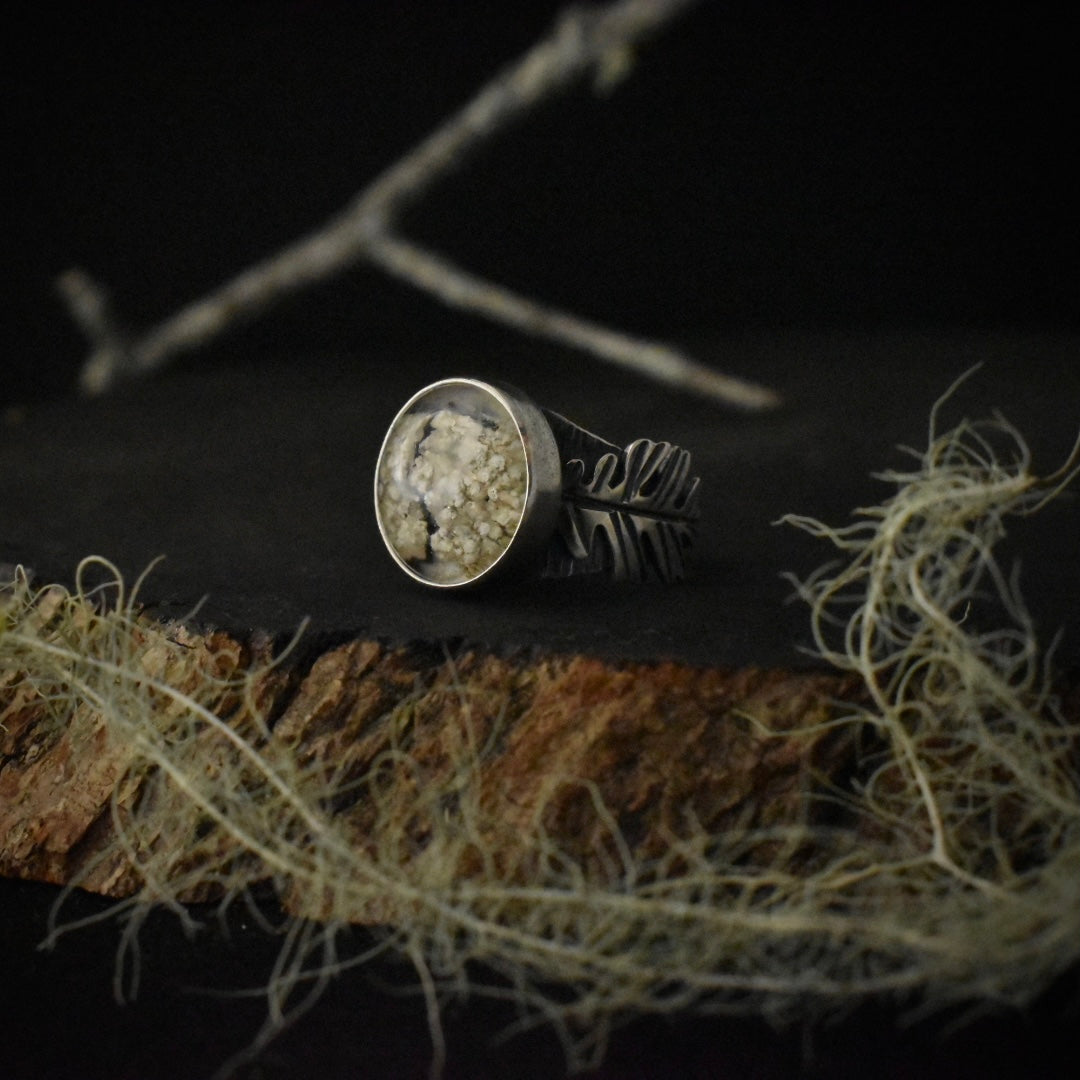 A handmade sterling silver statement ring, with a setting of real lichen preserved in clear resin, and its elements formed to look like oak leaves.