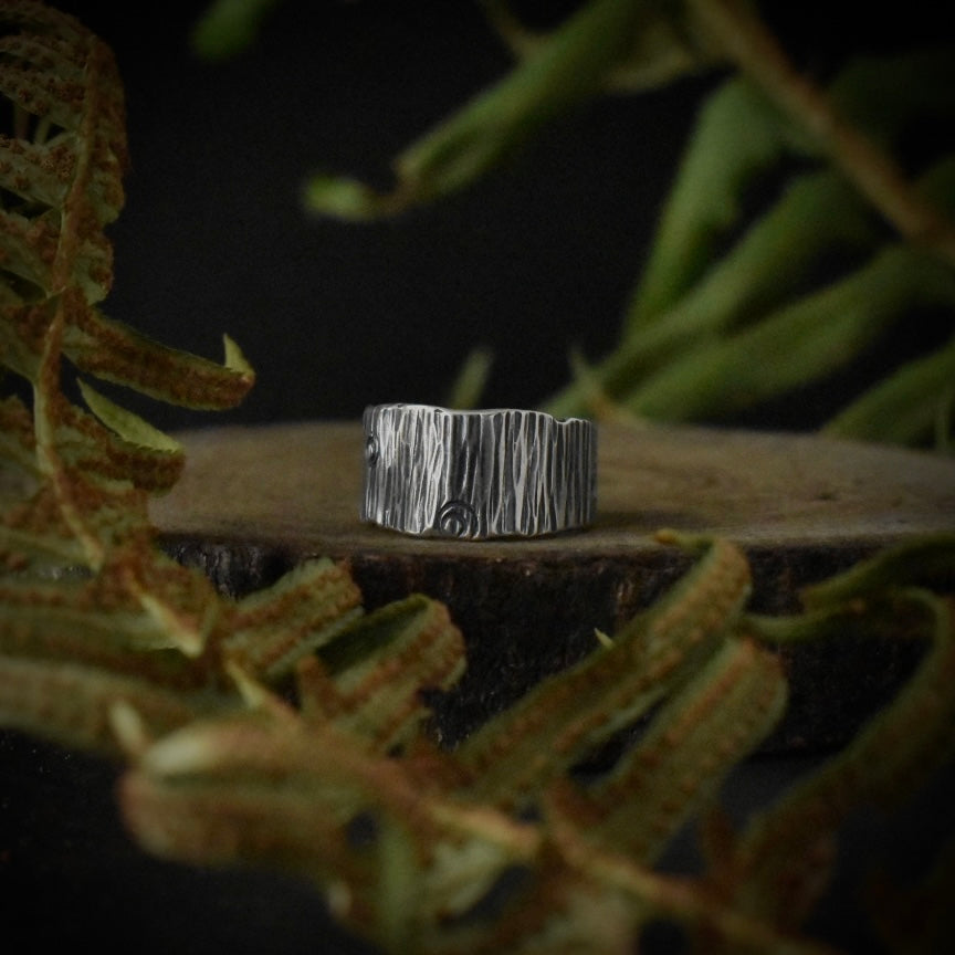 A handmade sterling silver band ring, stamped and textured to look like tree bark.