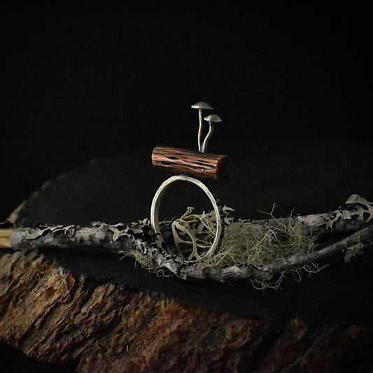 A handmade mixed metal statement ring, with copper formed and textured to look like a wooden log and two sterling silver mushrooms growing on top.