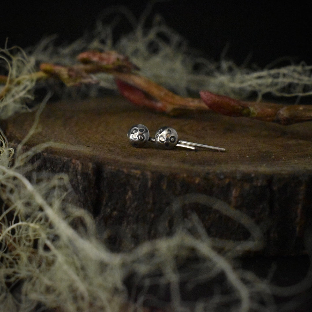 The tops of the Tiny Toadstool Stud Earrings, showing the details of their sterling silver mushroom caps and ear wires.