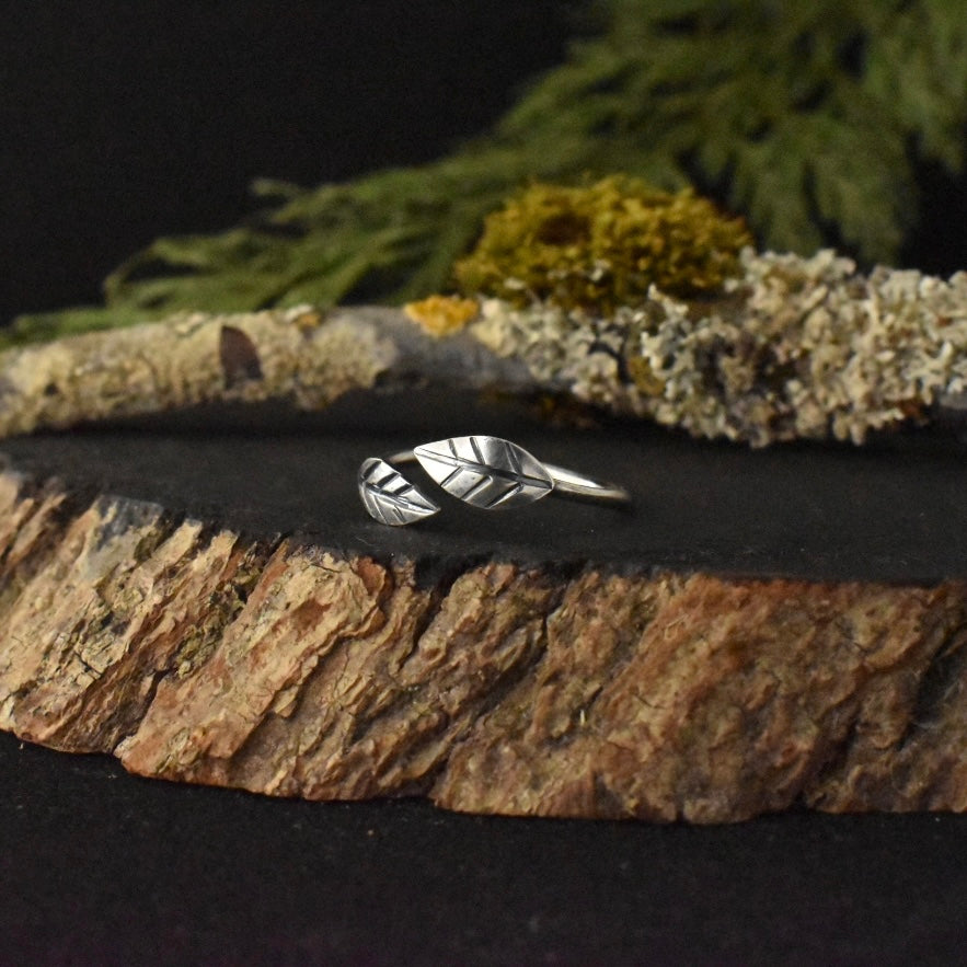 A handmade sterling silver ring, with two elements stamped and textured to look like small leaves.