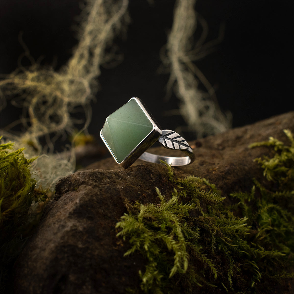 A dynamic pyramidal point of blue-green aventurine is set in a rounded bezel beside a sterling silver leaf, atop this handmade statement ring.