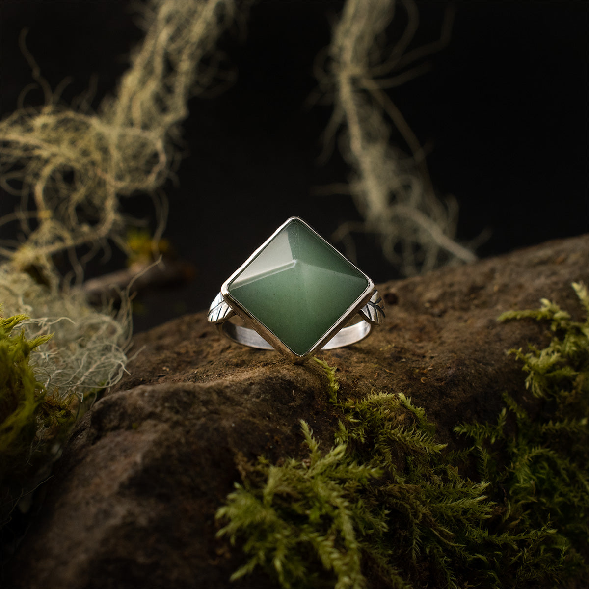 Top-down of the Aventurine Pyramid Double Leaf Ring, flanked by two sterling silver leaves, its energetic green stone is oriented on point, giving it a diamond shape when worn.