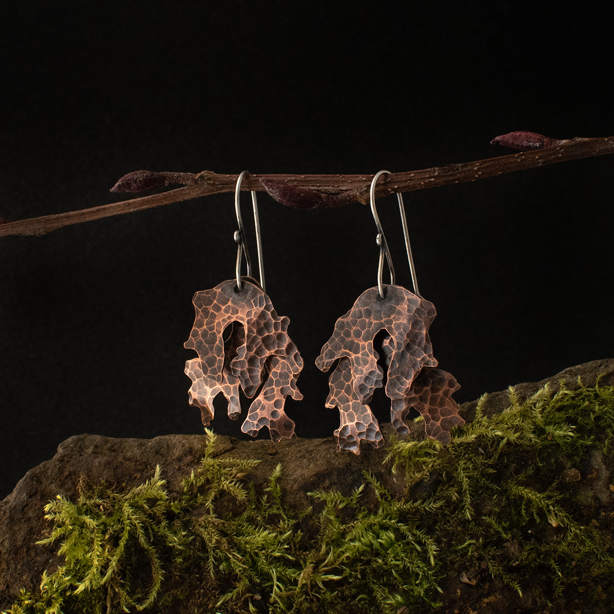 A pair of copper dangle earrings, each stamped and textured by hand like layers of lichen.