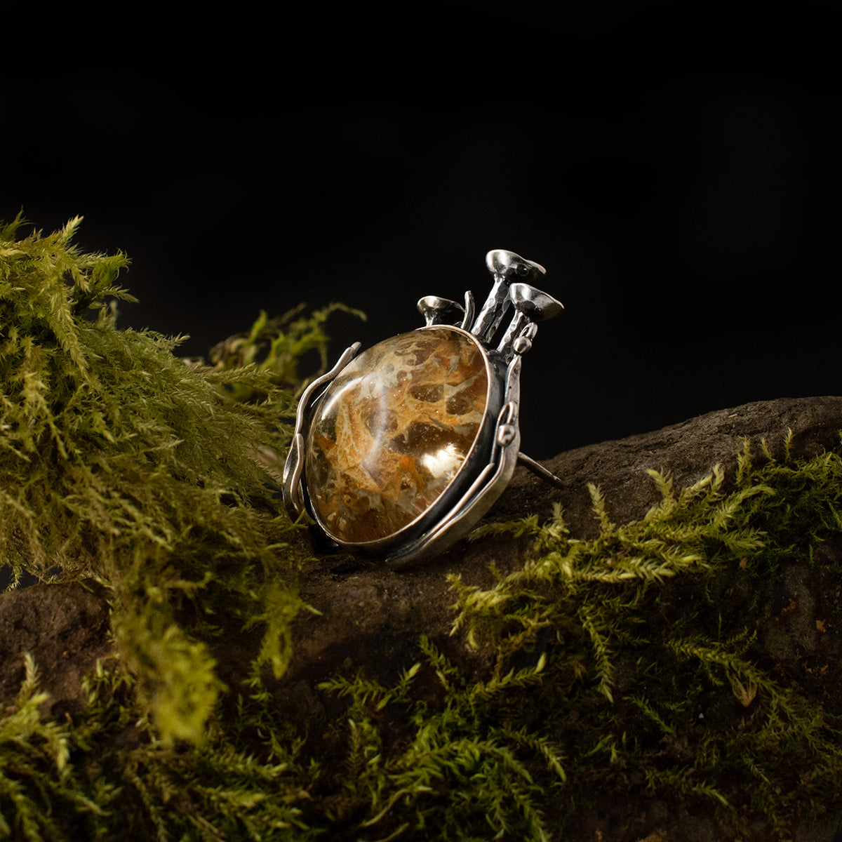 A three-quarter view of the Lichen Love Brooch, its real lichen setting is surrounded by 3D lichens and grasses, a miniature still life of the forest floor.