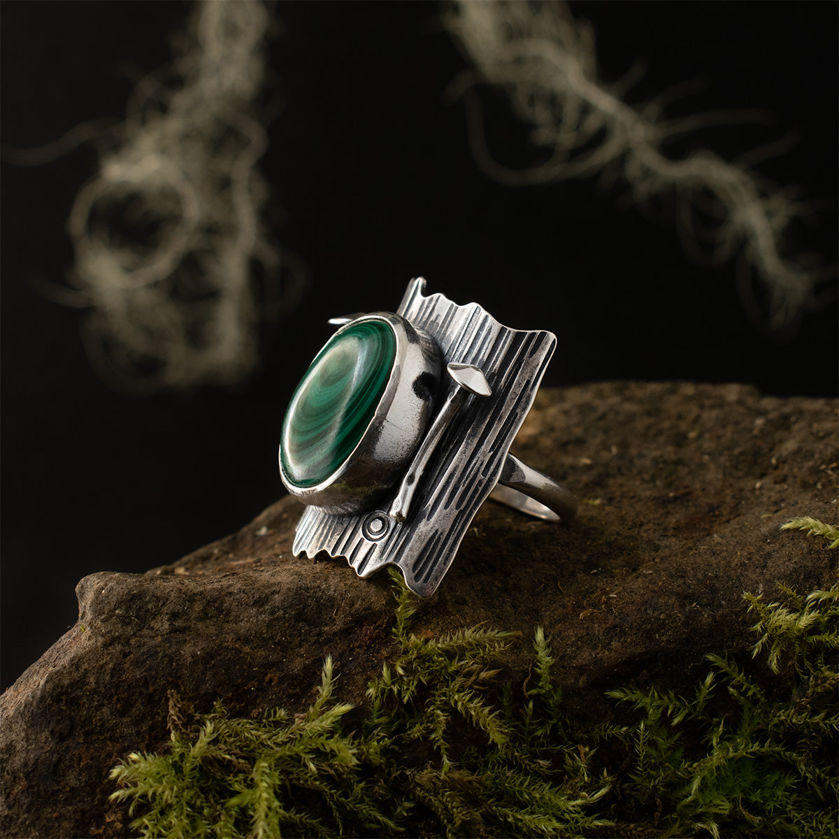 The right side of the Malachite Tree Trunk Ring, showing one of its sculpted sterling silver Mycena, tucked between a towering bezel and curling background of bark.