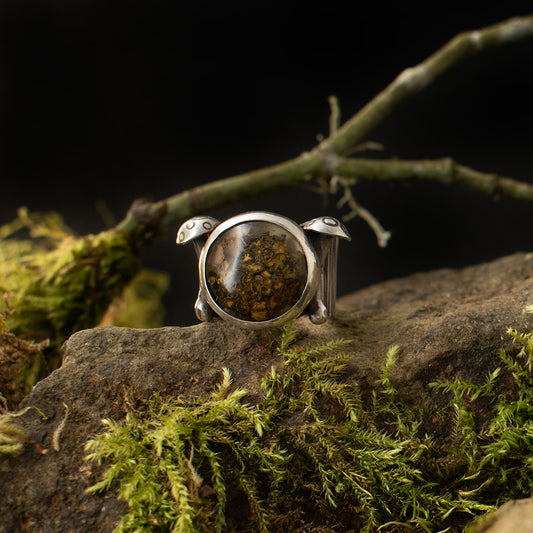 A handmade sterling silver statement ring, with a setting of real lichen preserved in clear resin, flanked by two elements formed like mushrooms.